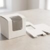 9x9x8 cm white window packaging box assembled next to flat-packed cartons on neutral background